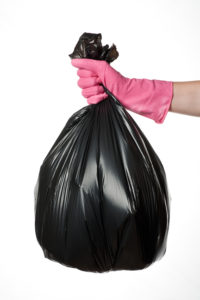 Hand holding a full black plastic trash bag