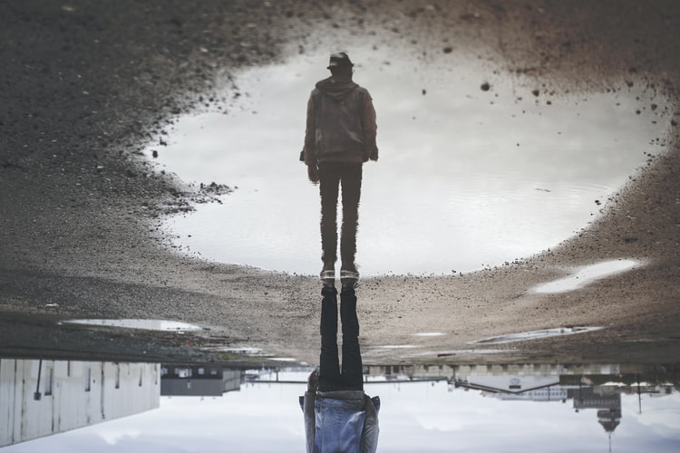 Man's reflection on body of water. Photo from Randy Jacob on Unsplash