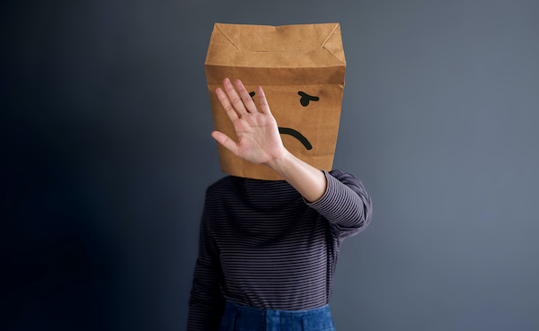 person with a frowny-faced bag on their head